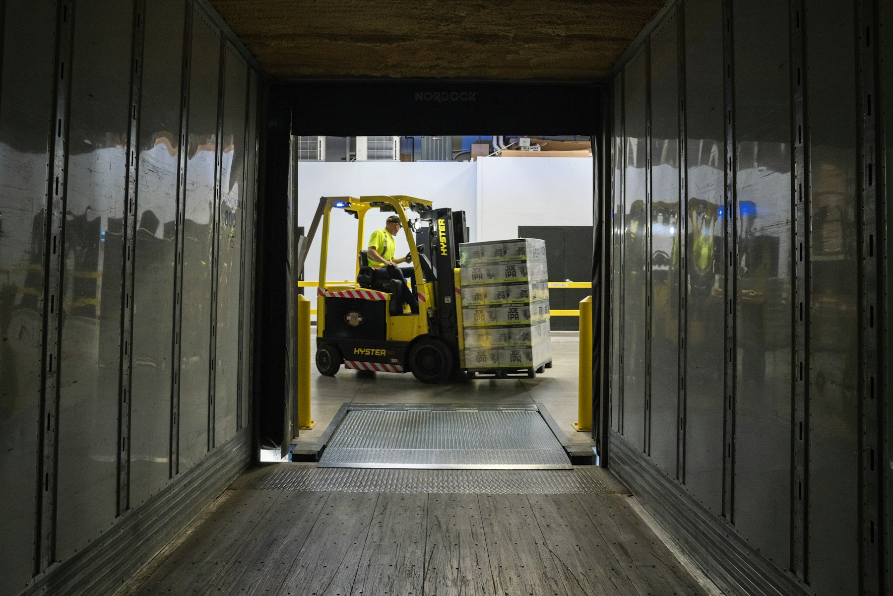 Forklift operator loading pallets into a trailer at a dock door