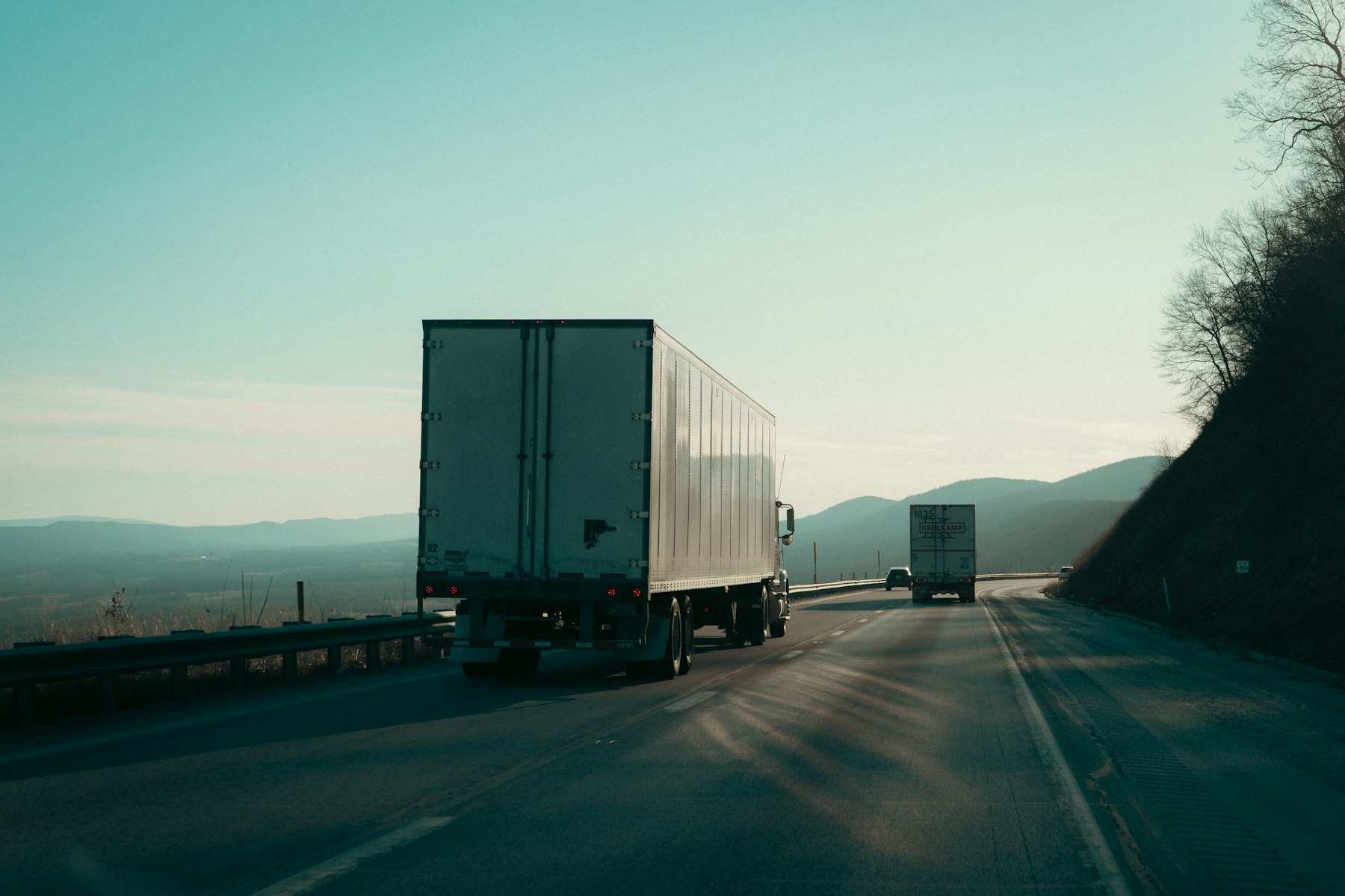 Semi truck pulling a trailer down the highway at dusk