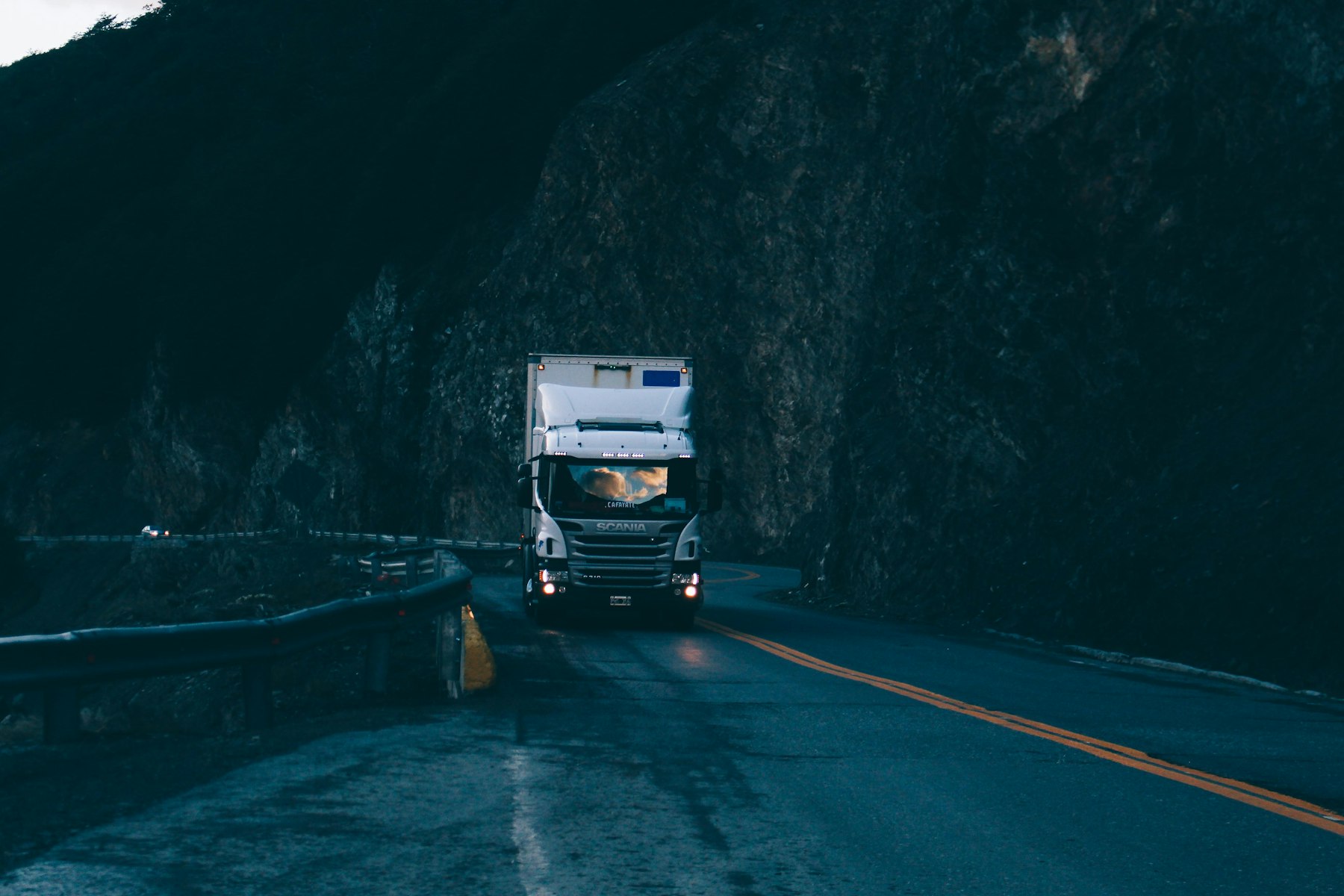 Semi truck coming through a mountain road in the evening