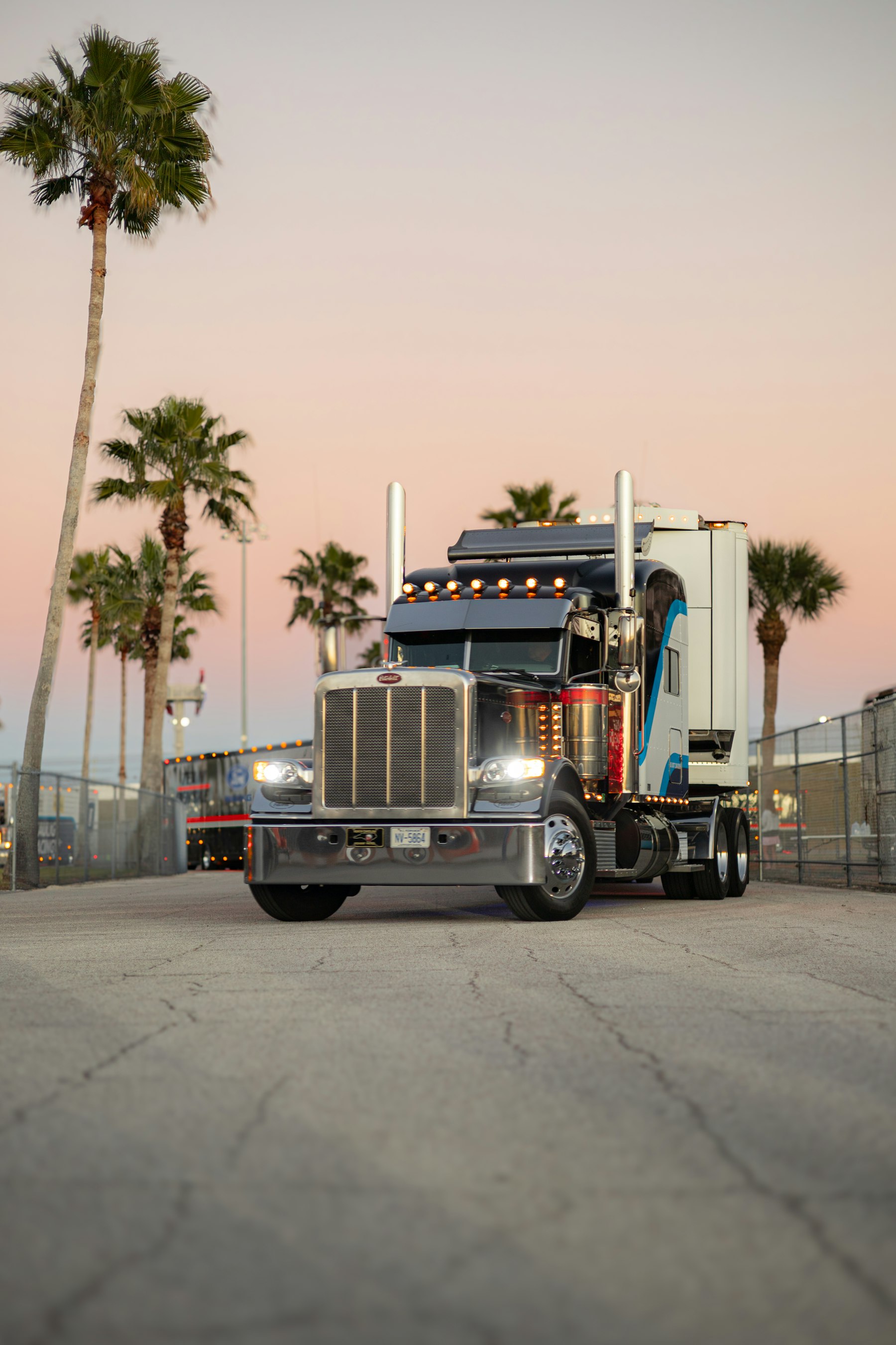 Long-hood semi truck parked at sunset with a dry van trailer