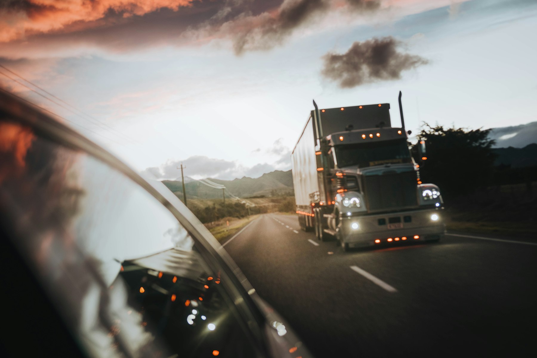 Semi truck at speed seen in a side mirror on an open highway