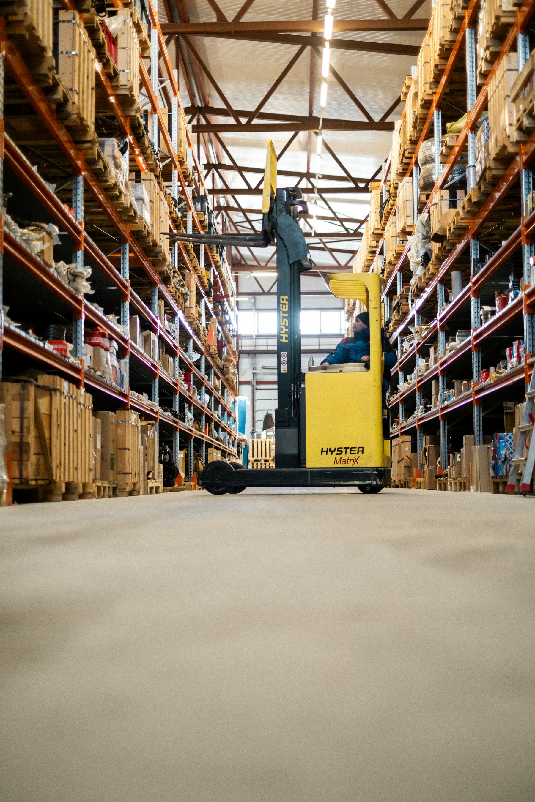 Reach truck operator moving pallets in a racked warehouse